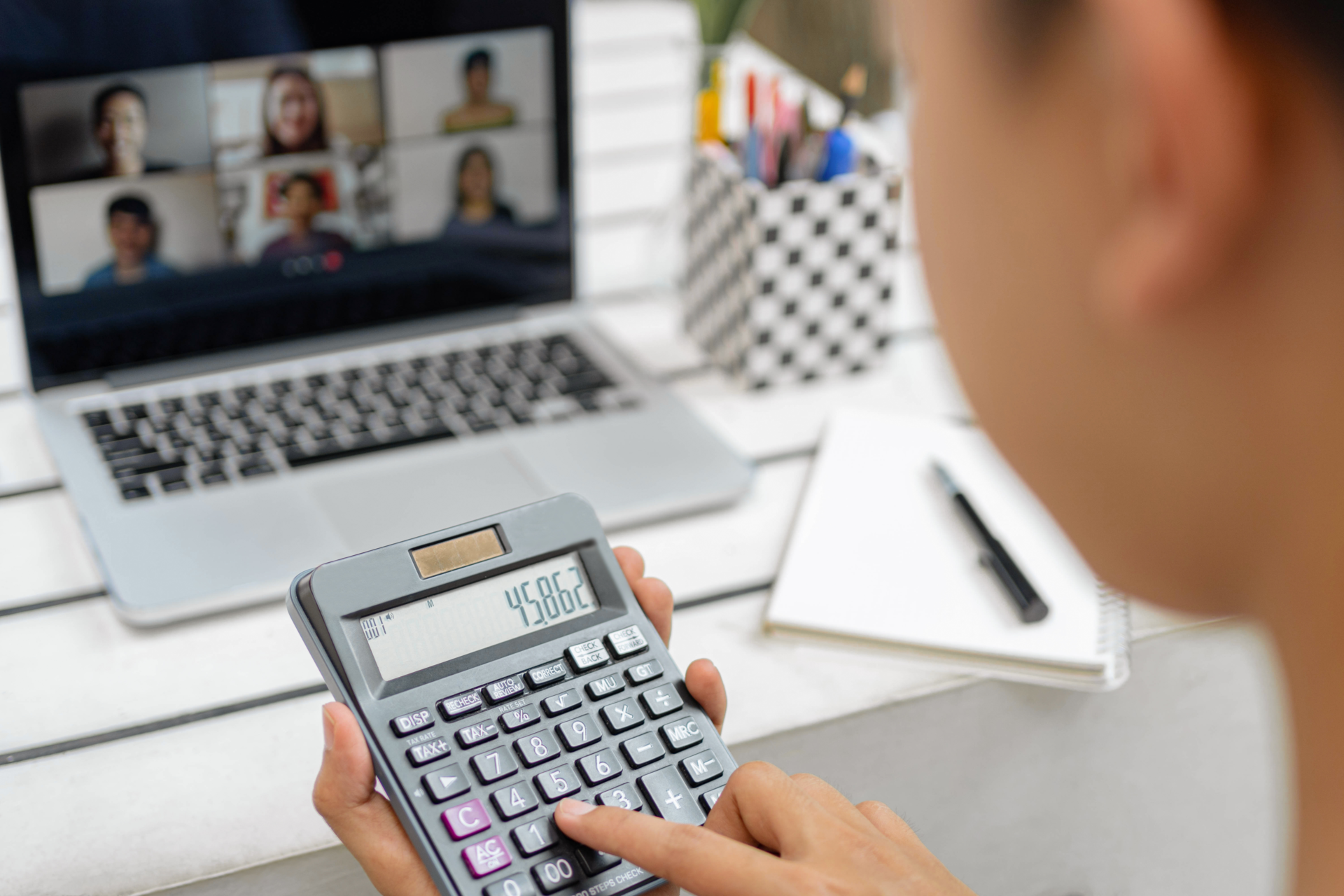 Online studying concept the man in plain white T-shirt feeling quite happy and holding the calculator for calculating numbers in accounting class.