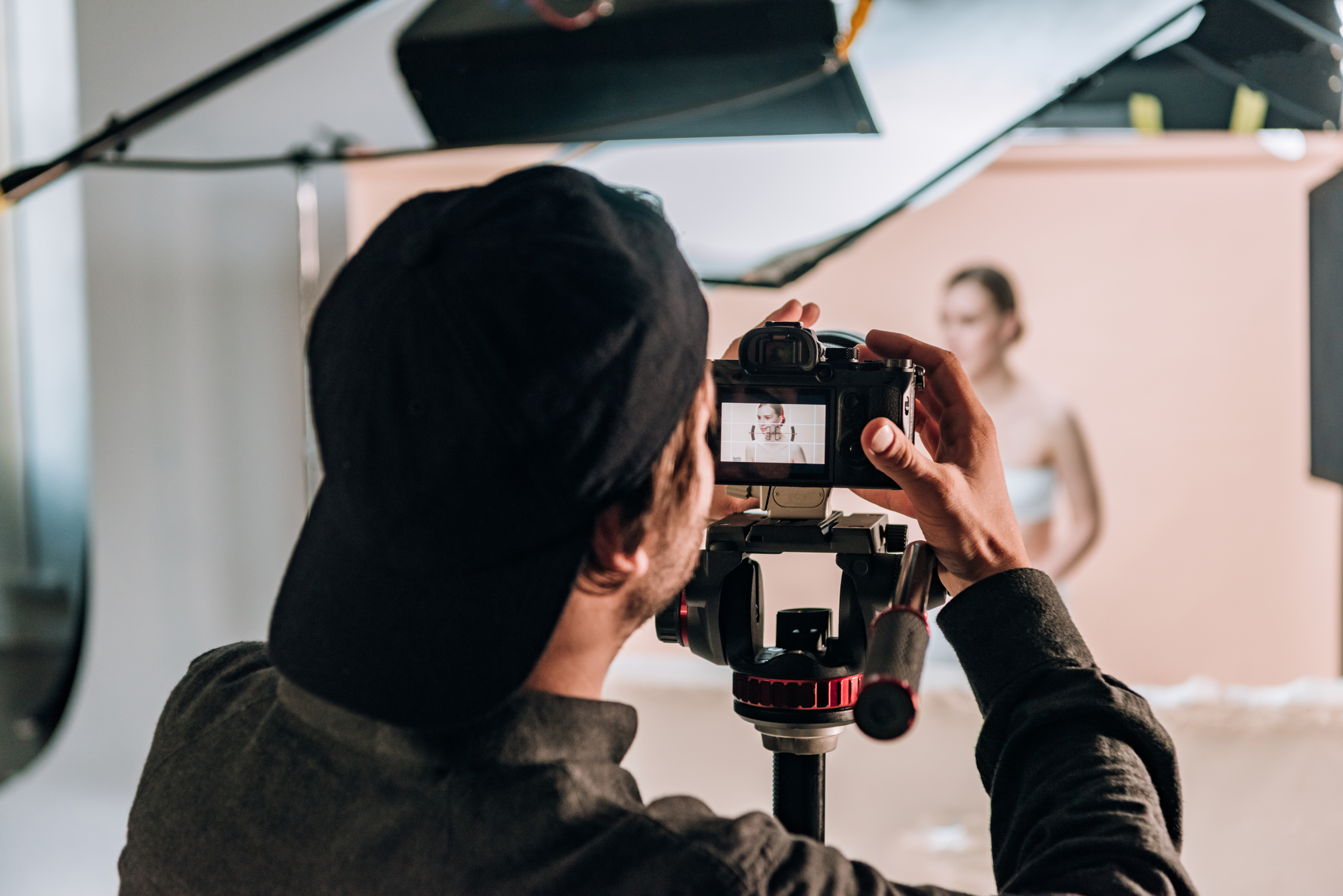 Selective focus of videographer with camera working with beautiful woman in photo studio