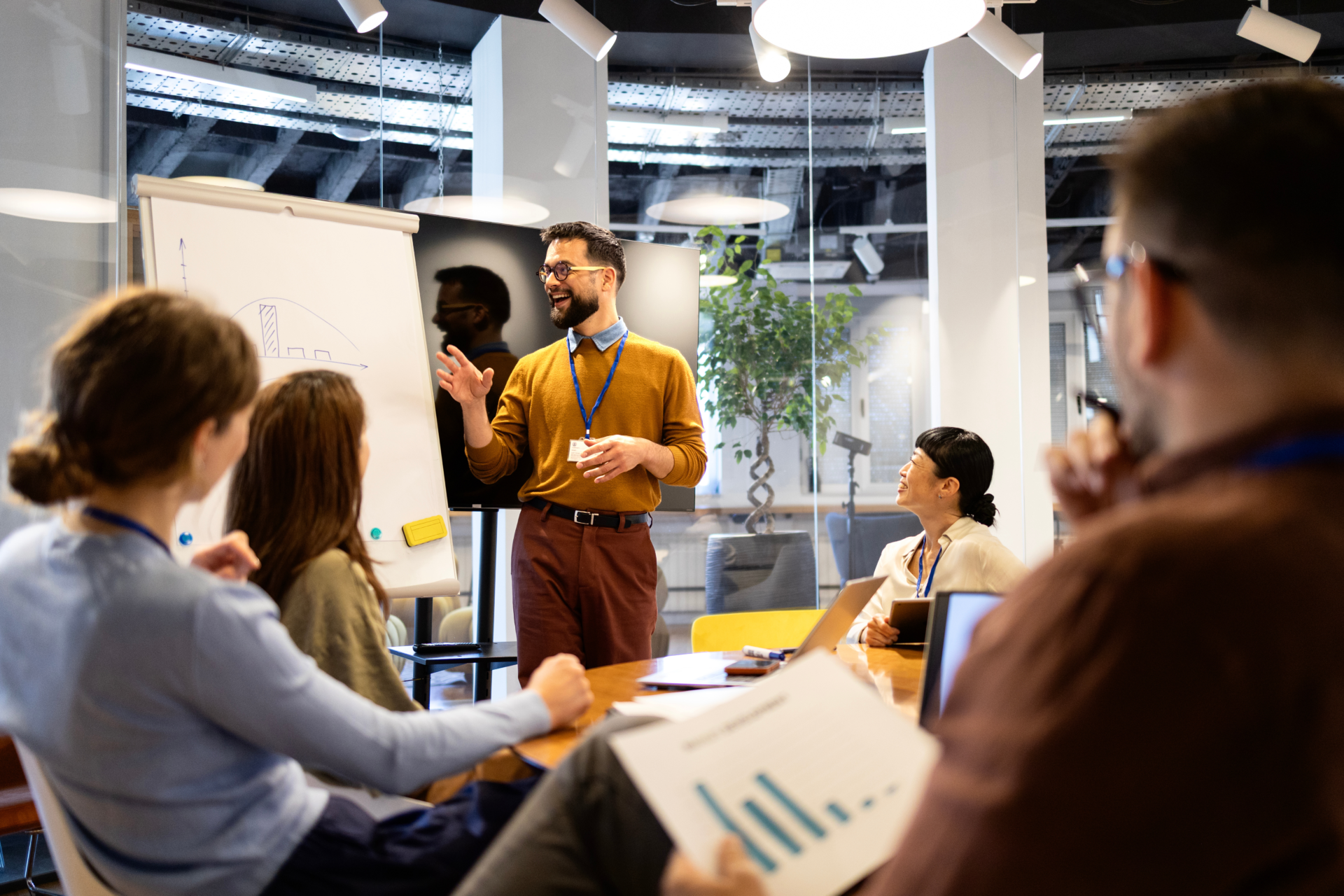 Diverse business team collaborating during a meeting. Man presenting on whiteboard to colleagues in a contemporary workspace