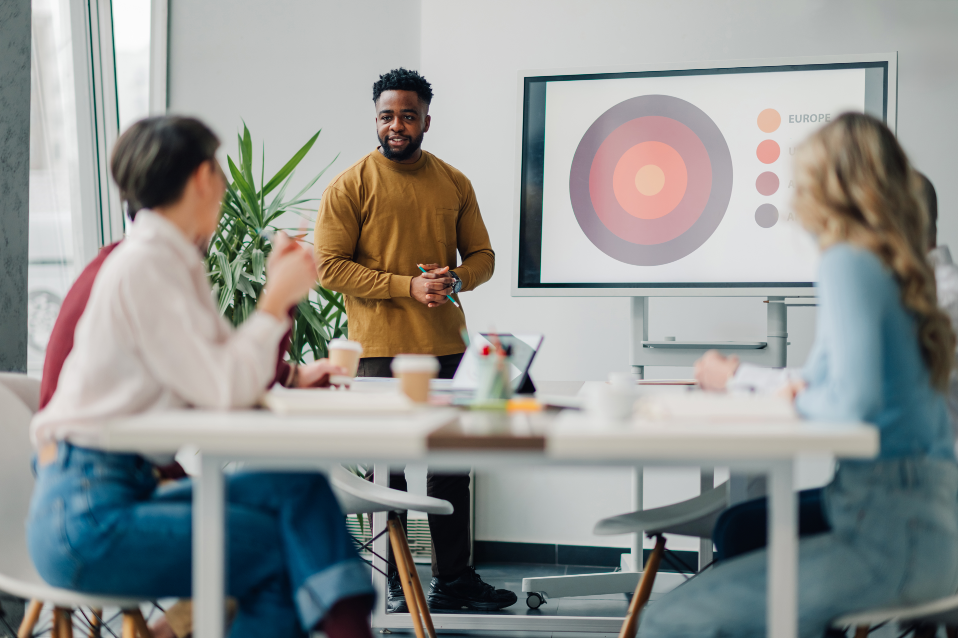 Marketing manager leading a presentation on europe during a team meeting in a modern office, utilizing a digital whiteboard to enhance communication and teamwork among colleagues